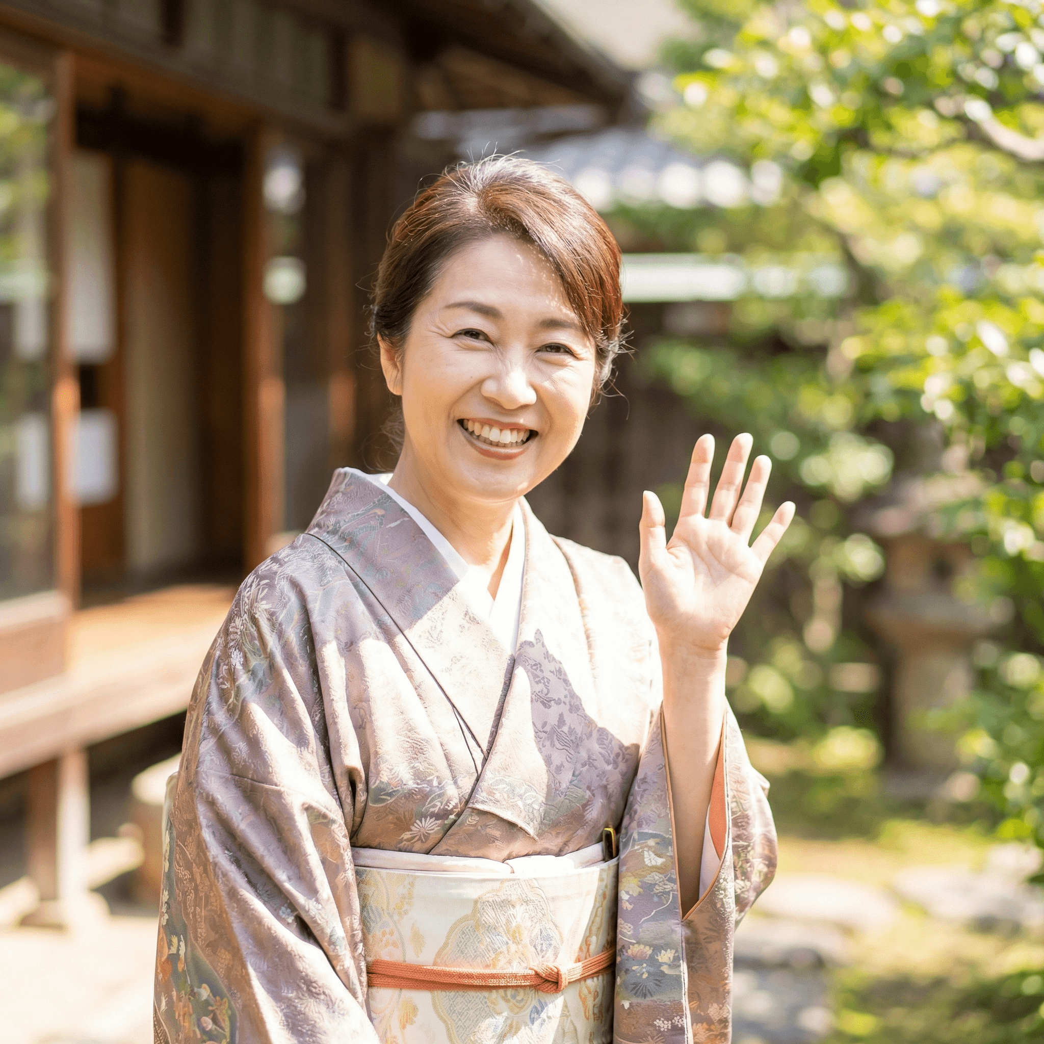 着物姿で笑顔で手を振る女性のバストアップ